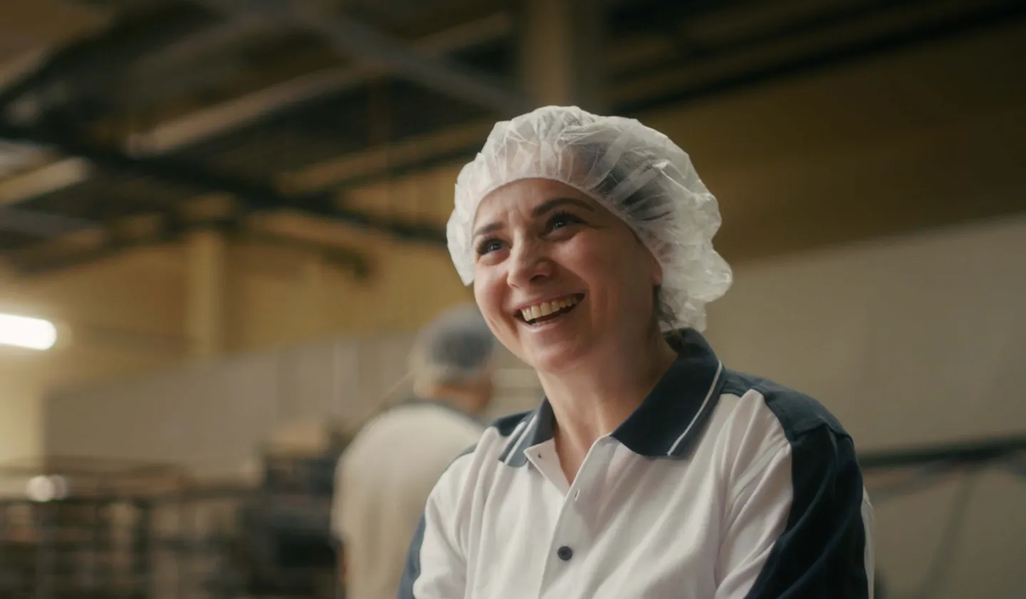 Bäckerin mit Kopfhaube die lächelt.